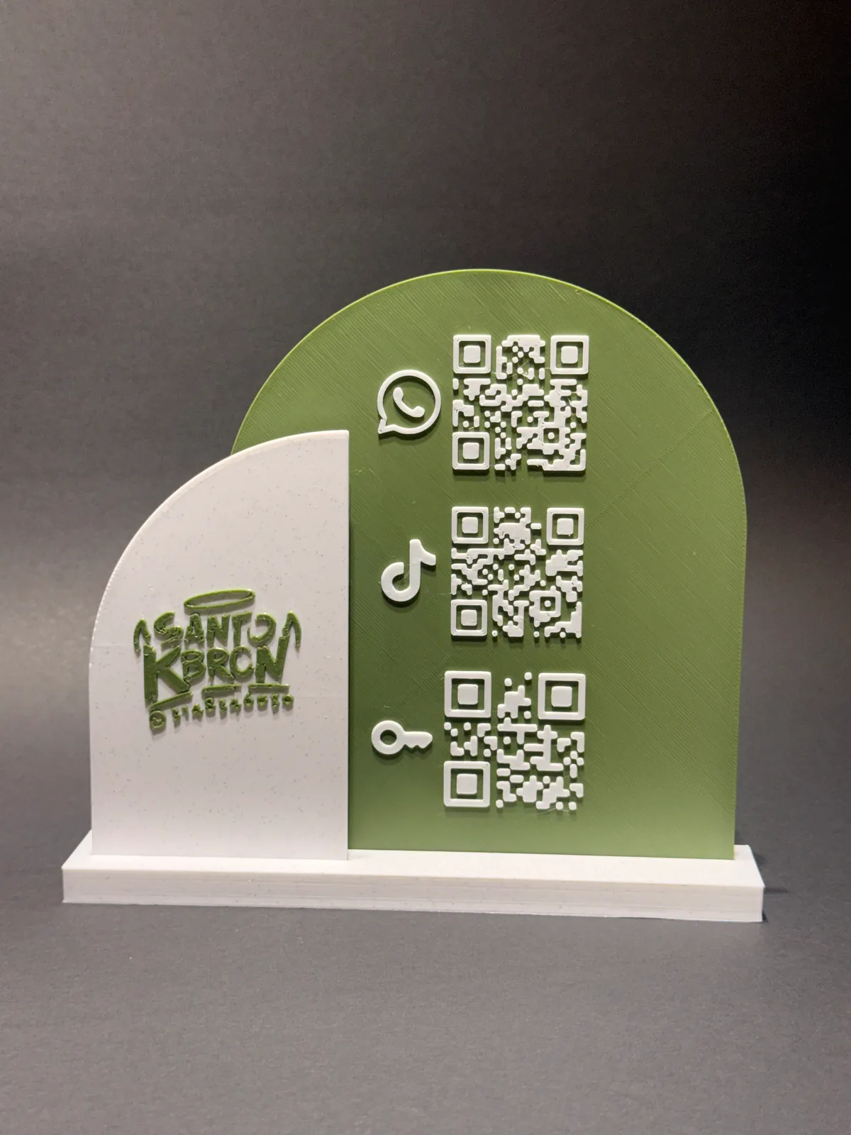 Placa QR con base verde y blanca de frente sobre fondo gris de estudio, con el logo del negocio en relieve en el panel blanco y tres códigos QR en el panel verde — Solid Lab 3D, Colombia